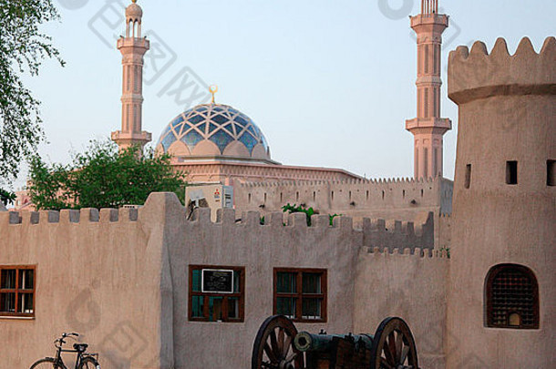 站在传统阿拉伯建筑外的老圣典，背景是阿拉伯联合酋长国迪拜的一座清真寺
