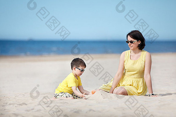 年轻的母亲和儿子在沙滩上玩耍