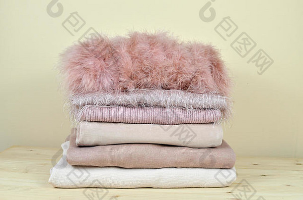 一堆不同材料的粉色服装-羽毛、棉、羊毛、灯芯绒-放在木架上