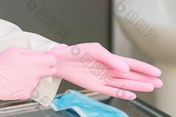 医生在医院特写镜头中戴上粉红色的手套。