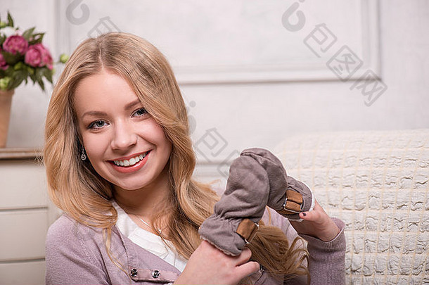 年轻的有吸引力的女人持有婴儿连指手套室内拍摄