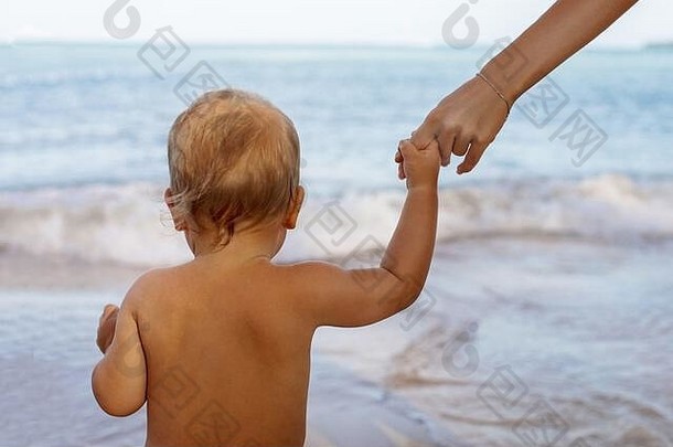 海滩上，一个小孩和一个没有脸的妈妈手牵手