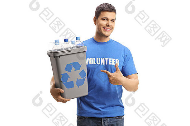 微笑的男志愿者拿着一个塑料回收箱，里面有瓶子，指着白色背景上的孤立物