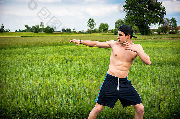 赤膊上阵的运动型年轻男子在农村户外练武