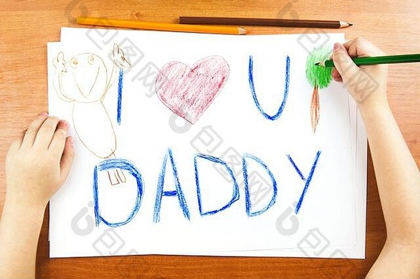 <strong>父亲节</strong>的概念。孩子们用手在木桌上画卡片，上面写着“<strong>我爱你</strong>，<strong>爸爸</strong>”，还有红色的心，还有彩色铅笔。