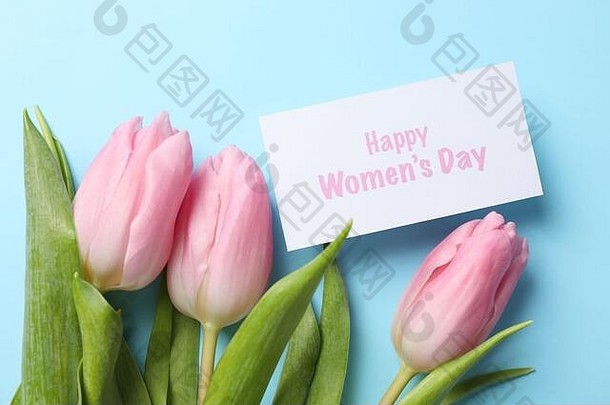 粉色郁金香和蓝色背景上的“妇女节快乐”字样，特写