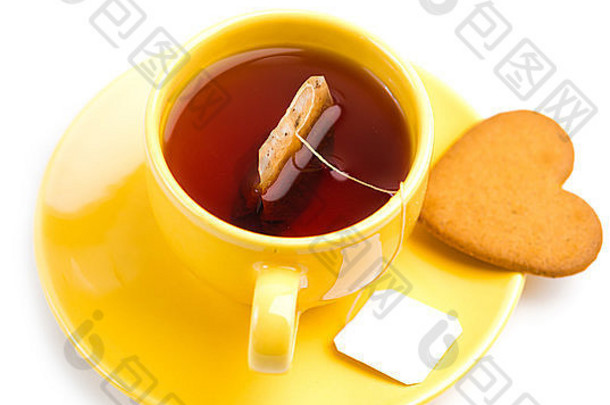 黄色茶杯，茶包和心形饼干在白色表面隔离