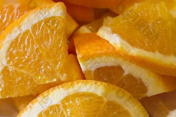 美味多汁的橙色水果片，含有健康的维生素。许多带有果皮和果肉的橙子块等待着品尝，例如美味的夏季派对鸡尾酒。