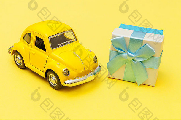 简单设计黄色复古玩具车，在时尚的黄色背景上隔离车顶上的礼品盒。圣诞新年生日情人节庆祝活动呈现浪漫理念。