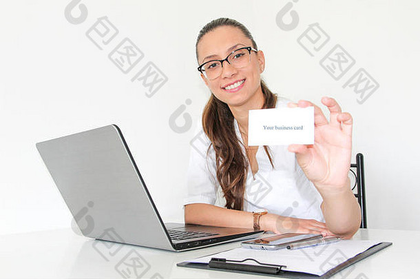 一位办公室里拿着笔记本电脑的年轻女医生手里拿着一张名片