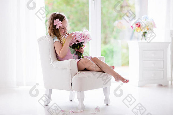女孩闻牡丹花花束坐着白色椅子阳光明媚的卧室托儿所室内花女孩