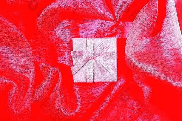 红色丝绸质地的<strong>银色</strong>礼品盒。<strong>情人节</strong>背景，贺卡。浪漫庆典的概念。平面布置，俯视图。