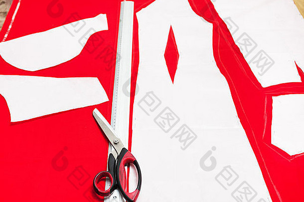 钳工用剪刀、尺子和剪下的羊毛织物，用于在桌上裁剪红色连衣裙