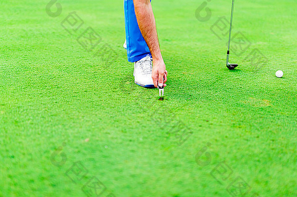 高尔夫球手在绿草表面上修理凹坑