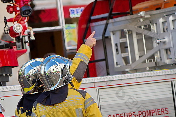 瑞士日内瓦，两名戴头盔的消防员在消防车旁讨论