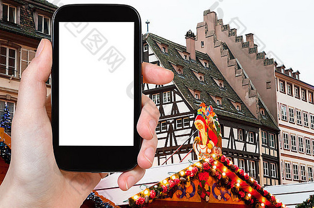 旅游理念-在智能手机上拍摄中世纪欧洲小镇斯特拉斯堡的圣诞市场的游客照片
