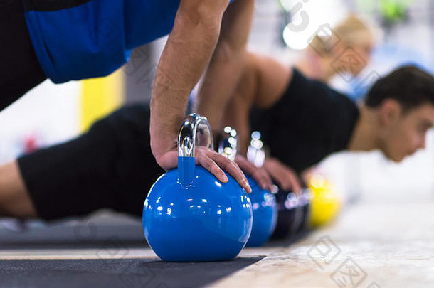 集团年轻的健康的运动员俯卧撑壶铃交叉健身健身房