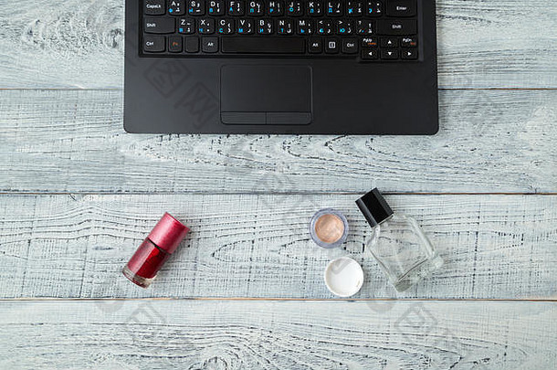 书桌妇女的工作场所。笔记本电脑、香水和化妆品。从顶部看的景色。平铺