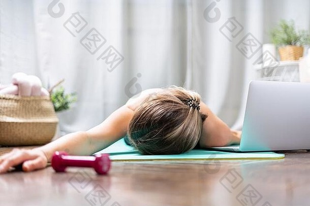 女人睡着了。运动和锻炼后感到疲倦。过度训练概念。筋疲力尽的女人躺在地板上，在剧烈的有氧训练后休息