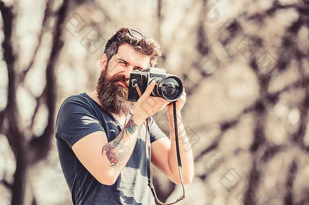 留着胡子的成熟时髦人士。留胡子的男人。自然的照片。记者或记者。复古摄影设备。戴夏季眼镜的时髦男人。带着相机的野蛮摄影师。自信的摄影师。