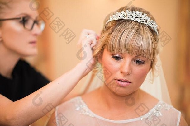 一位年轻美丽的未来新娘在准备婚礼、准备婚礼、由专业人士做头发和化妆的过程中为她的婚礼做准备
