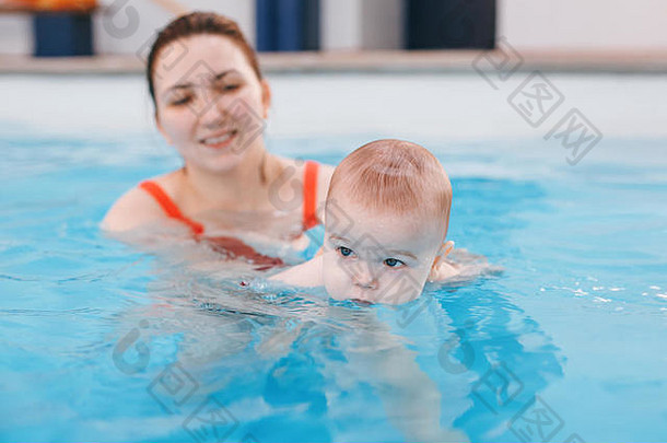 白人白人母亲训练她的新生婴儿在游泳池中漂浮。婴儿在水中潜水。健康积极的生活方式。家庭活动与早期疾病