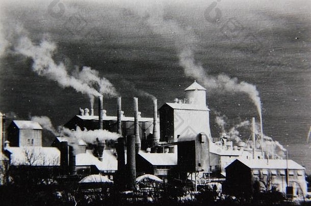 精美的70年代复古黑白极端摄影作品，拍摄的是一个正在工作、污染严重的工厂，烟囱正在喷涌污染。