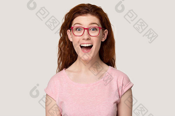 兴奋的戴眼镜的红头发女孩对胜利感到惊讶