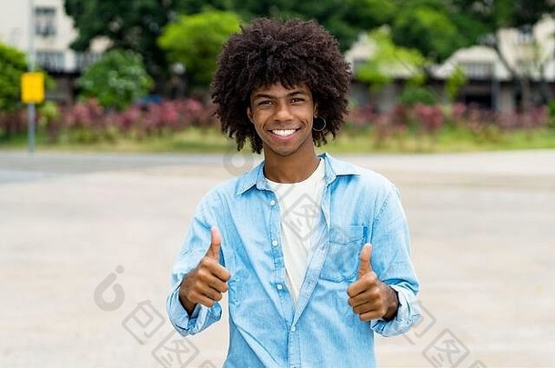 在城市的夏天，快乐的非裔美国时髦青年在户外竖起大拇指