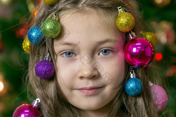 美丽的小女孩在头发上编织圣诞树装饰品。