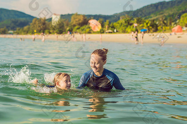 女儿童游泳教练正在教一个快乐<strong>的男孩</strong>在海里游泳