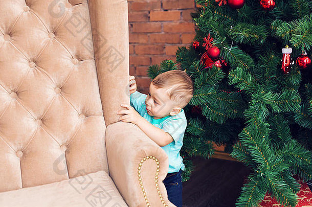 有趣的男孩站沙发圣诞节树色彩斑斓的圣诞节球