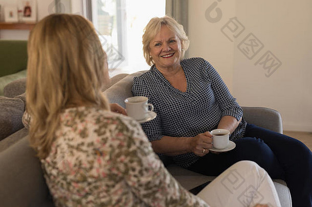 母亲和女儿在客厅喝咖啡时相互交流