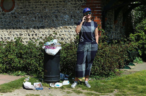 在垃圾桶边打电话的女人。马丁·帕尔风格。英国布莱顿