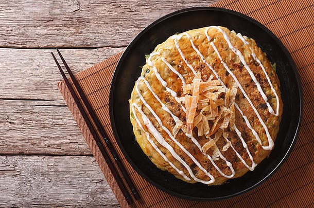 一张桌子上放着日本的okonomiyaki和筷子。水平俯视图