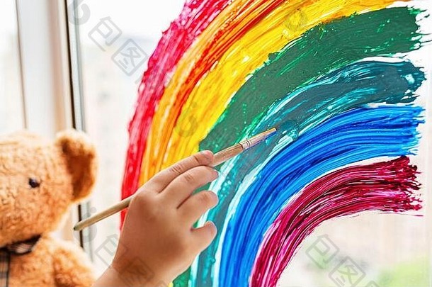 儿童绘画彩虹在2019冠状病毒疾病在家检疫。靠近窗户的女孩。在家社交媒体上开展预防冠状病毒的活动，让我们共同努力