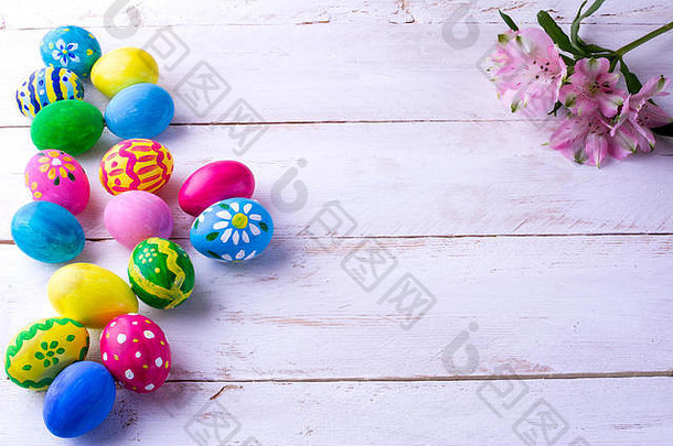 彩色手绘复活节彩蛋和白色木板上的粉红色花朵。复活节背景。复活节的象征。带副本的俯视图