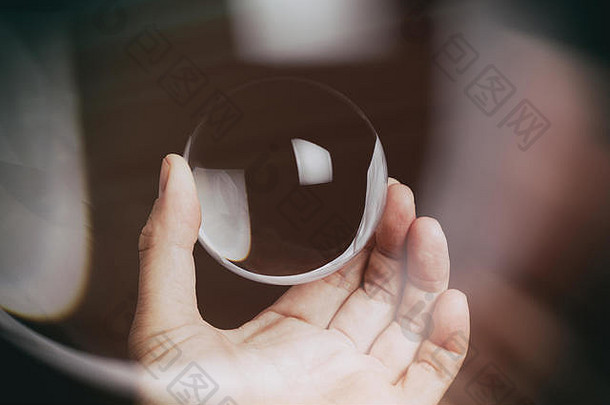 手拿着一个背景为黑色的透明水晶球。