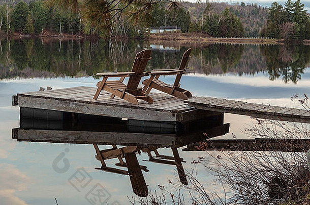 加拿大安大略湖上一个木制码头上两张板条躺椅的宁静景象