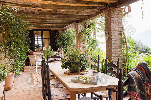 西班牙别墅阳台上的木桌和雕刻椅上有郁郁葱葱的室内植物