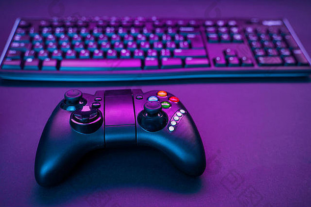 紫色桌面背景上的键盘和操纵杆。