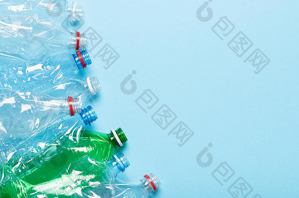 蓝色背景顶视图上的塑料瓶。回收塑料废物污染概念与空间接壤。