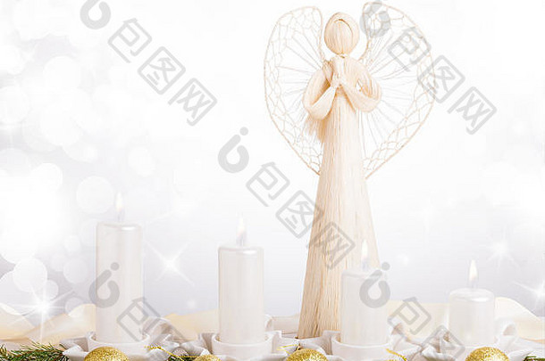 一位白色的天使和四支白色的降临蜡烛，圣诞树枝上装饰着金球。