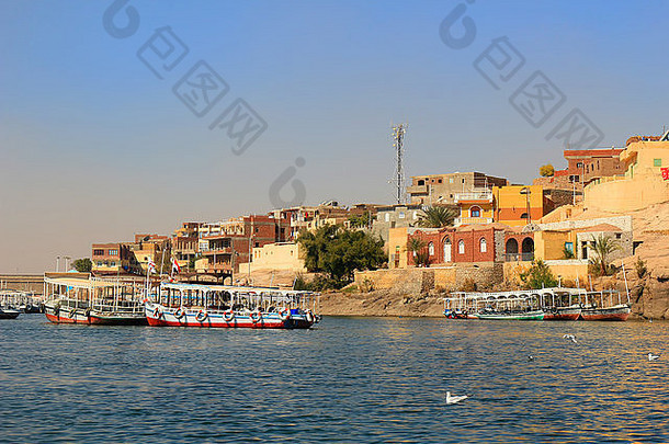 木船停靠在北非埃及的尼罗河沿岸，背景是房屋