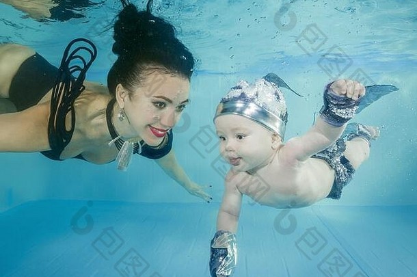 妈妈带着一个小儿子微笑着潜入游泳池