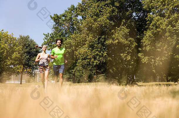 一对年轻夫妇在阳光明媚的夏日在大自然中奔跑