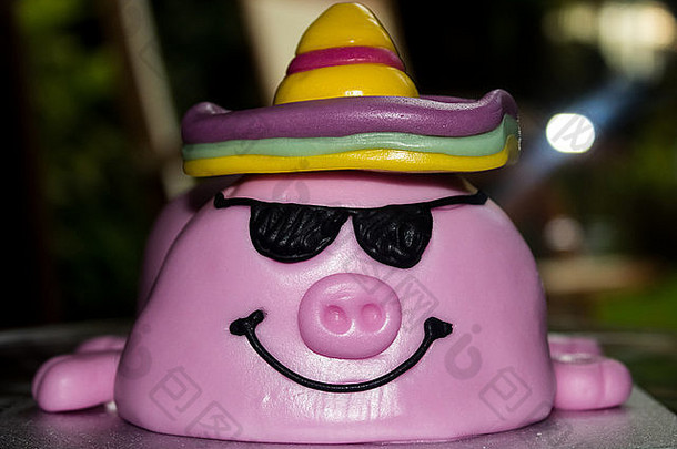 一头戴着冰罩衫和冰太阳镜的新奇猪生日蛋糕。