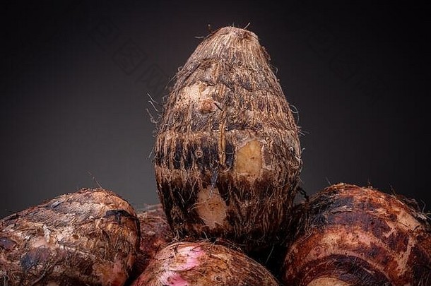 夫妇多毛的棕色（的）粉红色的生山药可食用的蔬菜当地的巴西市场黑暗灰色背景工作室低关键食物概念