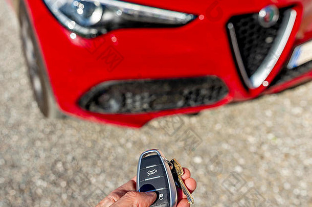 一只手操纵着一辆漂亮的红色意大利跑车阿尔法·罗密欧·斯泰维奥的遥控器