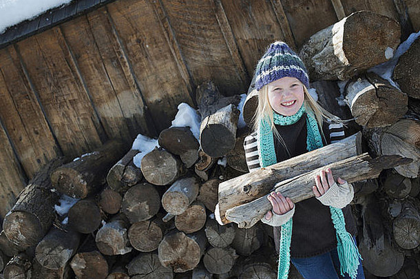 冬天的景色地上有雪一个女孩从木柴堆里拾柴